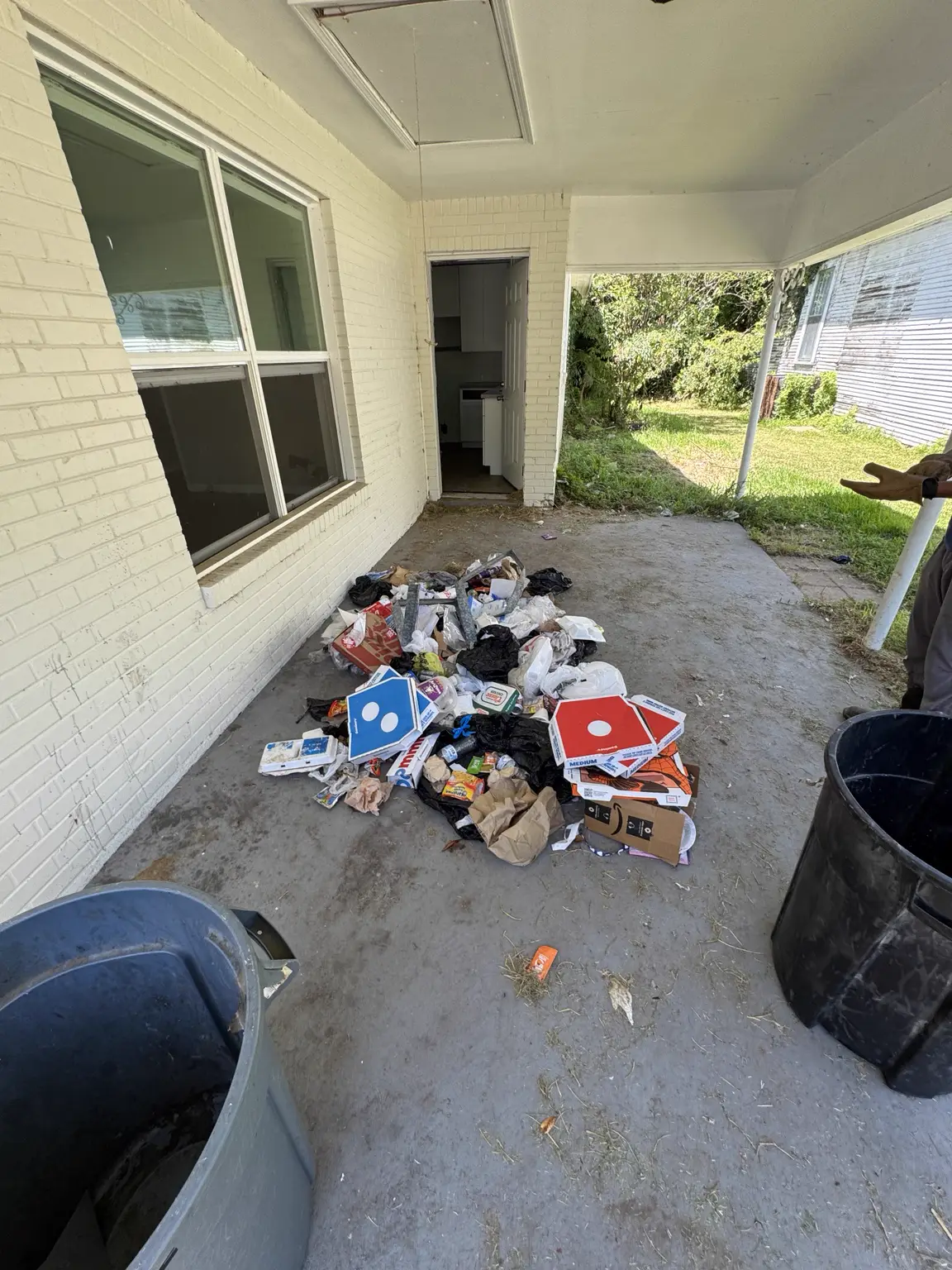 Covered porch before cleanup with a pile of household debris