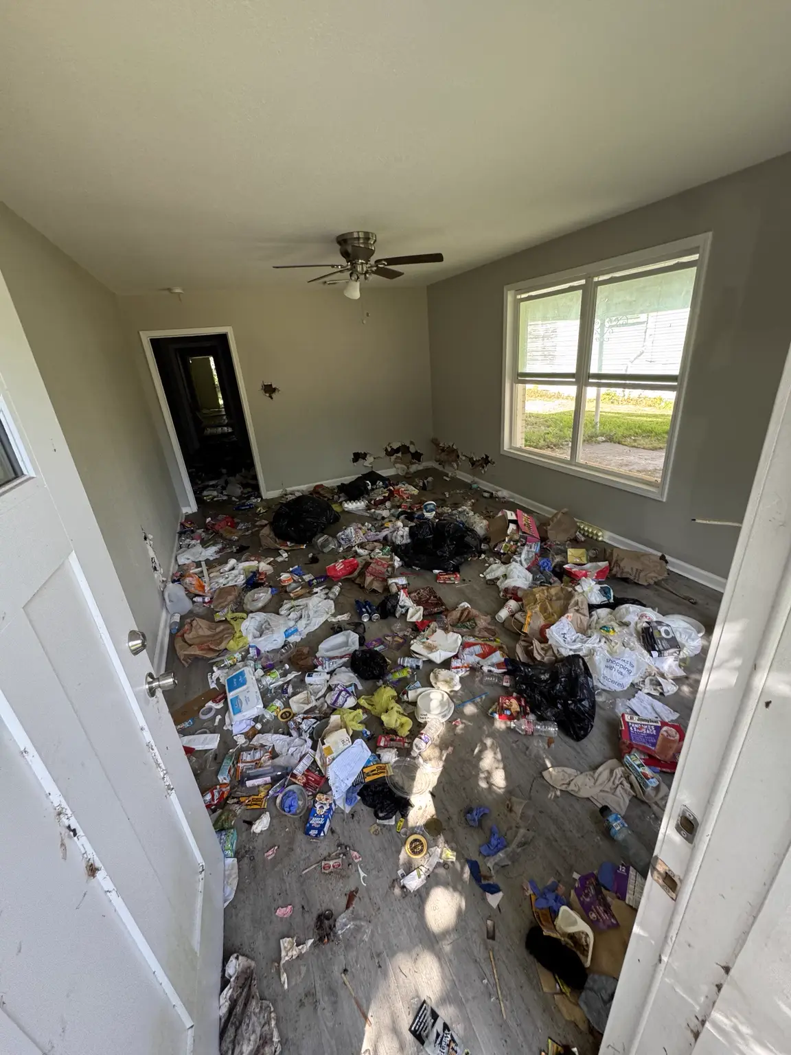 Additional room before the property cleanout with household debris across the floor
