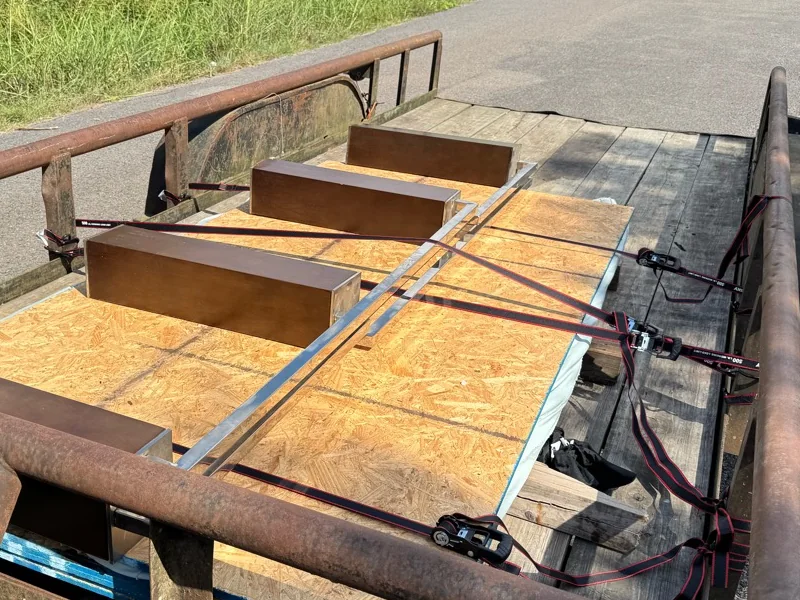 Disassembled glass-top dining table secured on a utility trailer for removal.